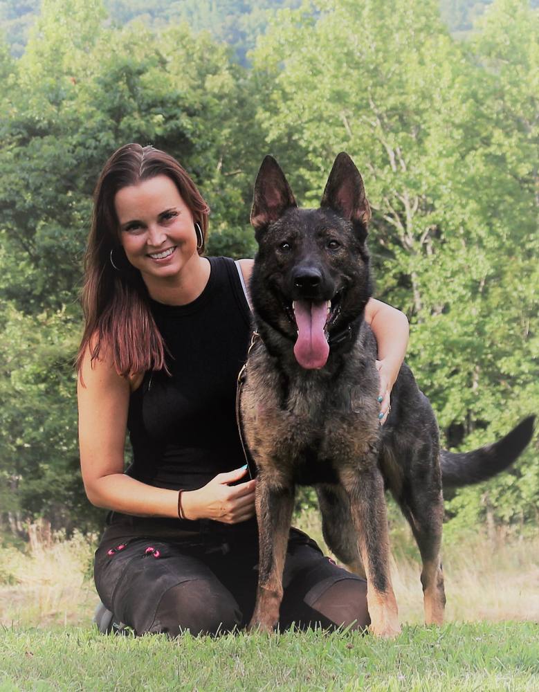Woman kneeling with her German Shepherd outdoors